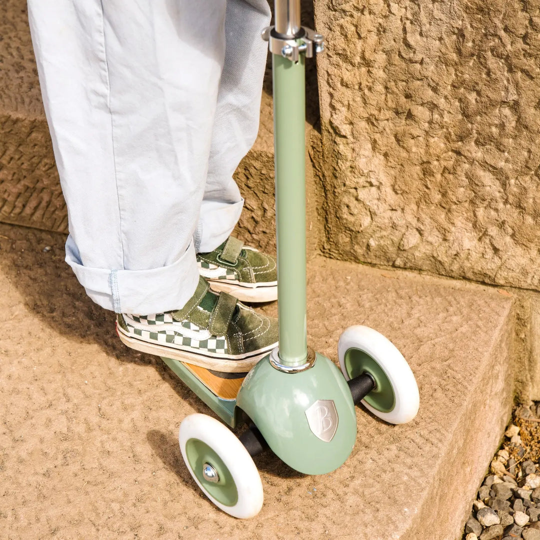 Close-up of front wheel and oak deck on sand with child wearing checkerboard trainers