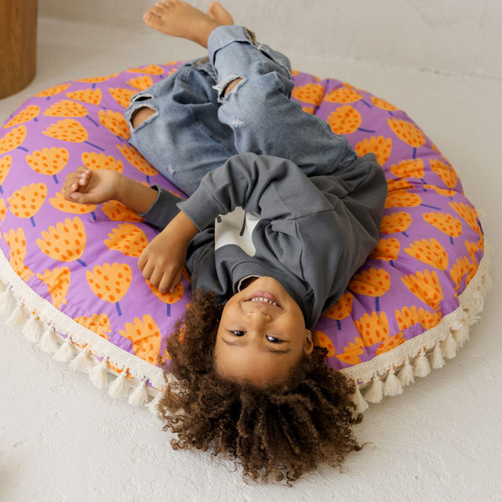 Close view of the vivid orange and violet tulip print on the MINICAMP floor cushion
