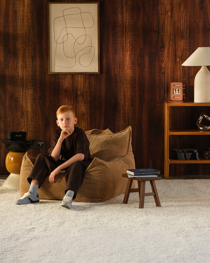Child seated in the Toffee Wigiwama Club Chair, ribbed corduroy fabric, styled living room