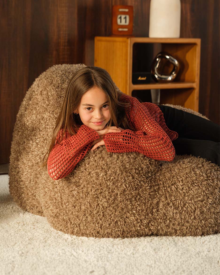 Truffle Wigiwama Momo Chair, child lounging sideways in the high pile YETI fabric
