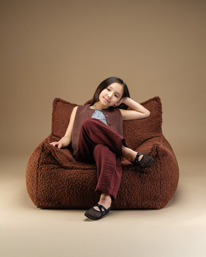 Child seated in the Warm Hazel Wigiwama Club Chair, curly Teddy fabric